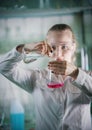 Chemical laboratory. Young blonde woman holding two flasks with liquid in it. About to transfuse the liquid