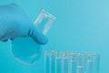 Gloved hand pours liquid from a flask into a test tube