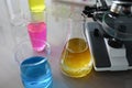 Chemical test tubes with multicolored liquid standing near microscope