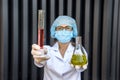 Chemist examining test tube with substance. She`s in protective uniform over grey abstract grey background Royalty Free Stock Photo