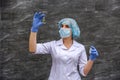 Chemist examining test tube with substance. She`s in protective uniform over grey abstract grey background Royalty Free Stock Photo