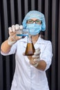 Chemist examining test tube with substance. She`s in protective uniform over grey abstract grey background Royalty Free Stock Photo