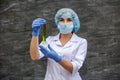 Chemist with flask making scientific experiment. She`s in protective uniform and gloves