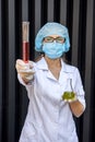 Chemist with flask making scientific experiment. She`s in protective uniform and gloves