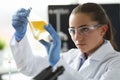 Chemist girl looks at flask with yellow liquid