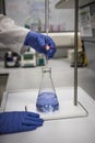 Chemist with gloved hands in a laboratory analysing a sample by titration Royalty Free Stock Photo