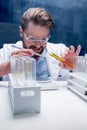 Chemist in goggles with reagents in tubes and tablet in laboratory