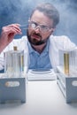 Chemist in goggles with reagents in tubes and tablet in laboratory