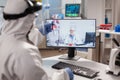 Chemist in ppe suit listening professional doctor on video call