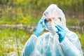 Chemist researcher in protective clothing examines infected plants