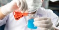 Chemist student boy pouring red liquid in erlenmeyer flask to beger glass chemistry with red liquid on biochemical experiment. Royalty Free Stock Photo