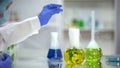 Chemist taking organic liquid sample from flask with plant, dermatology extract Royalty Free Stock Photo