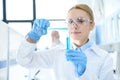 Chemist in white coat holding test tubes with reagents and making experiment