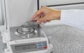 A chemist in a white coat is weighing white powder