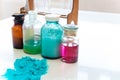 Chemistry bottles containing various substances of different colors standing on laboratory table seen over a pile of blue powder