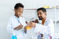 In chemistry classroom with many laboratory tools. A young African boy and male teacher in white lab coat help each other do Royalty Free Stock Photo