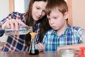 Chemistry experiments at home. Woman pouring the water into the flask from bottle using funnel. Royalty Free Stock Photo