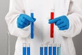 In a chemistry lab, a pharmacist holds test tubes with red and blue liquids. Medical experiment. Chemist working on a test with