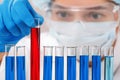 In a chemistry lab, a woman checks test tubes. Medical experiment. Chemist in safety glasses working on a test