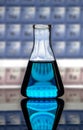 Chemistry laboratory conical flask on a reflecting surface and periodic table background