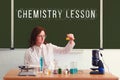 The chemistry teacher conducts tests with reagents sitting at the school table. Text on the blackboard