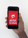 Selective focus of holding mobile and displayed Airtel 5G on a mobile device screen.