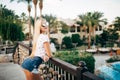 Cherful young woman in resort, holiday vacation, standing, posing next to the pool.