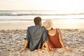 Cherish every sunset. Rearview shot of a middle aged couple watching the sunset on the beach.