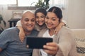 Cherish your family and love them forever. a happy young family taking selfies with a smartphone on the sofa at home. Royalty Free Stock Photo