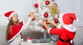 Cherished holiday activity. Kids in santa hats decorating christmas tree. Family tradition concept. Children decorating