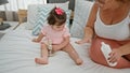 Cherished moments, mum and daughter\'s morning playtime on bed, applying skin treatment in cozy bedroom