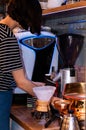 Barista standing near wooden counter and pouring dry coffee into dark paper cup
