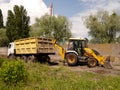 Cherkasy / Ukraine - May 25, 2019: Tractor loading, excavating the earth into a dump truck. Royalty Free Stock Photo