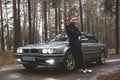 Chernigov, Ukraine - January 6, 2021: A guy stands near a BMW 7 E38 car on the road in the forest. Gloomy weather