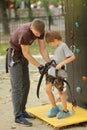 Sports instructor helping a child to put on a climbing harness