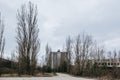 Telephone booth in a building with broken windows, shabby entrance in marble, with overgrown trees and grass in abandoned town of