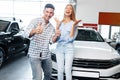 Cherrful young couple at the dealership buying a new car