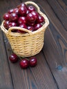 Cherries in the basket on the dark textured wooden planks