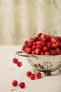 Cherries in a colander on a light wooden background. Royalty Free Stock Photo