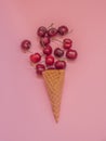 Cherries in a ice cream cone on pink