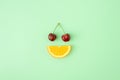 Cherries and orange slice on pastel green background. Creative summer fruit background. Food concept