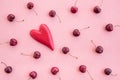 Cherries and red wooden heart on pink canvas