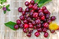 Cherries. Ripe red fruits on a wooden wicker surface and clover and dandelion in soft focus. Sunny day in springtime. Sweet fruits Royalty Free Stock Photo