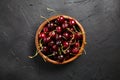 Cherries in a wooden bowl on a black stone table. Red ripe berries on a dark background, top view Royalty Free Stock Photo