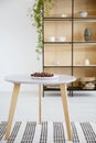 Cherries on wooden table on patterned carpet in white flat interior with shelves. Real photo