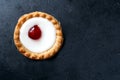 Cherry bakewell tart in foil case on dark background