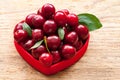 Cherry basket in red bowl. Cherry with leaves in heart. Fresh sweet cherries Royalty Free Stock Photo