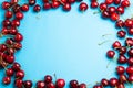 Cherry berries on a blue background top view.Background with a cherry on a sprig, Border. Royalty Free Stock Photo