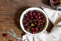 cherry berries in a metal bowl on a wooden table with vintage scissors and a linen towel. Top view. Royalty Free Stock Photo