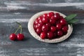 Cherry berries on a metal plate with ornament. On a wooden dark background